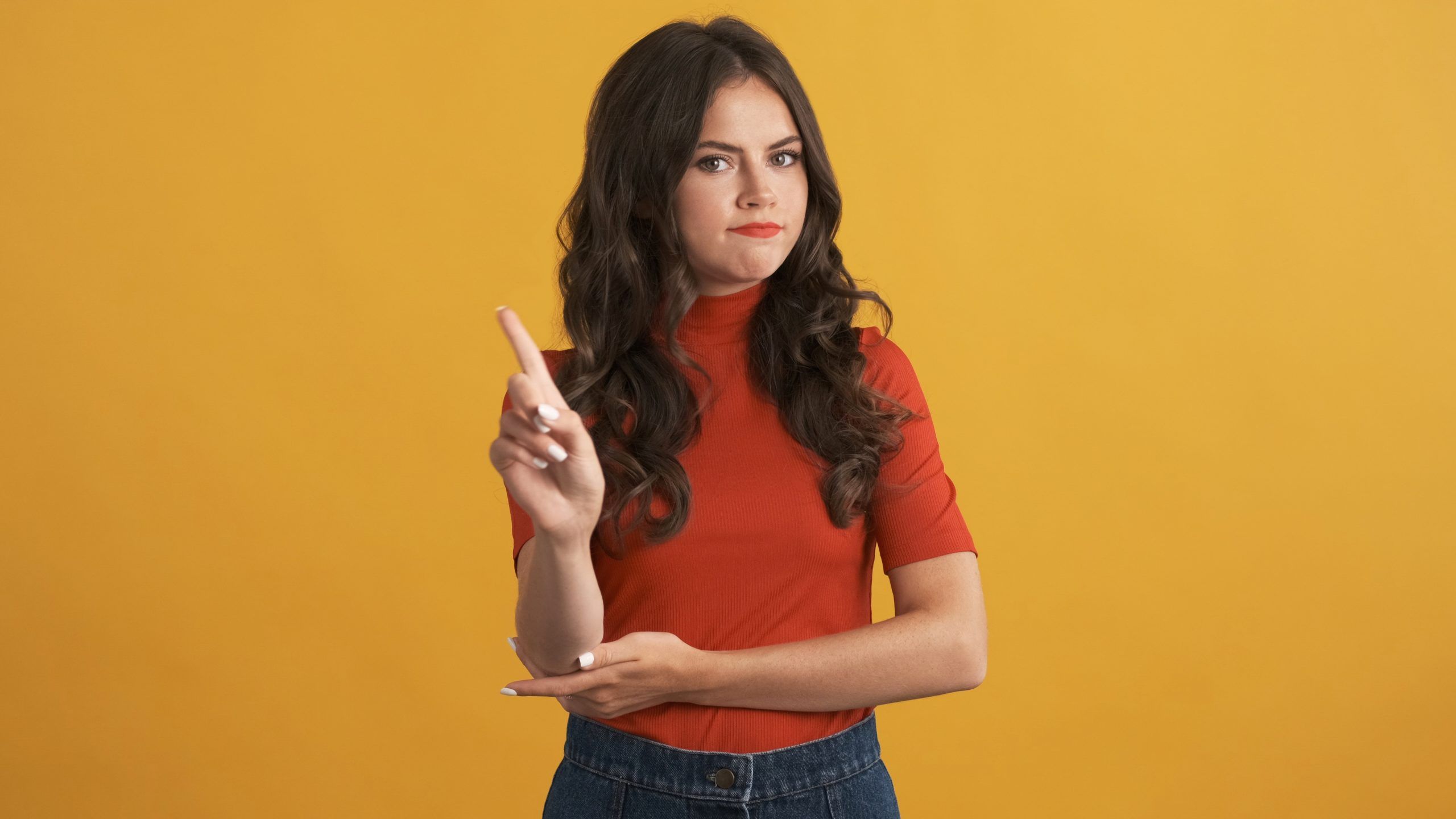Serious girl in red top confidently showing no gesture on camera