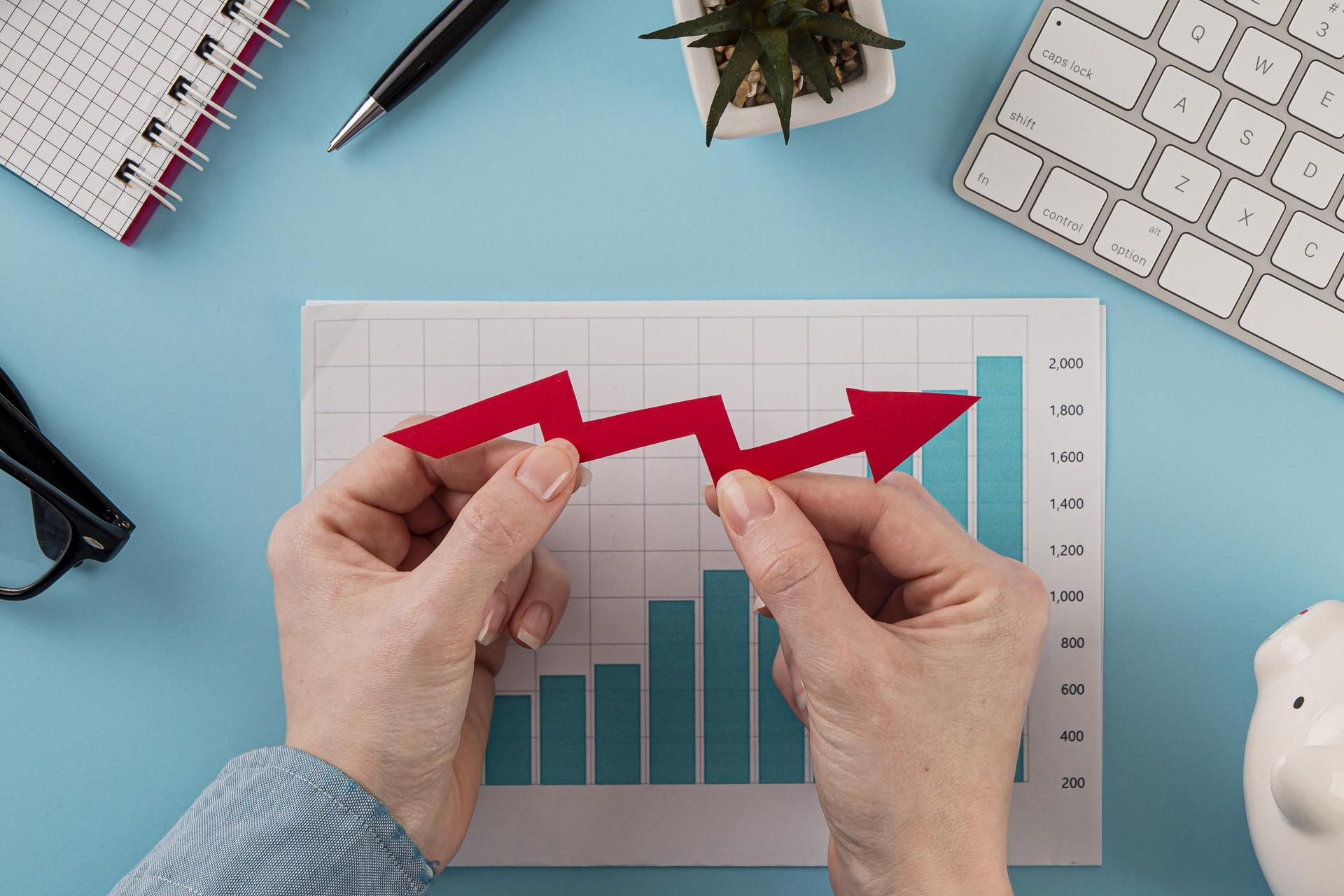 vista-superior-elementos-comerciales-tabla-crecimiento-manos-sosteniendo