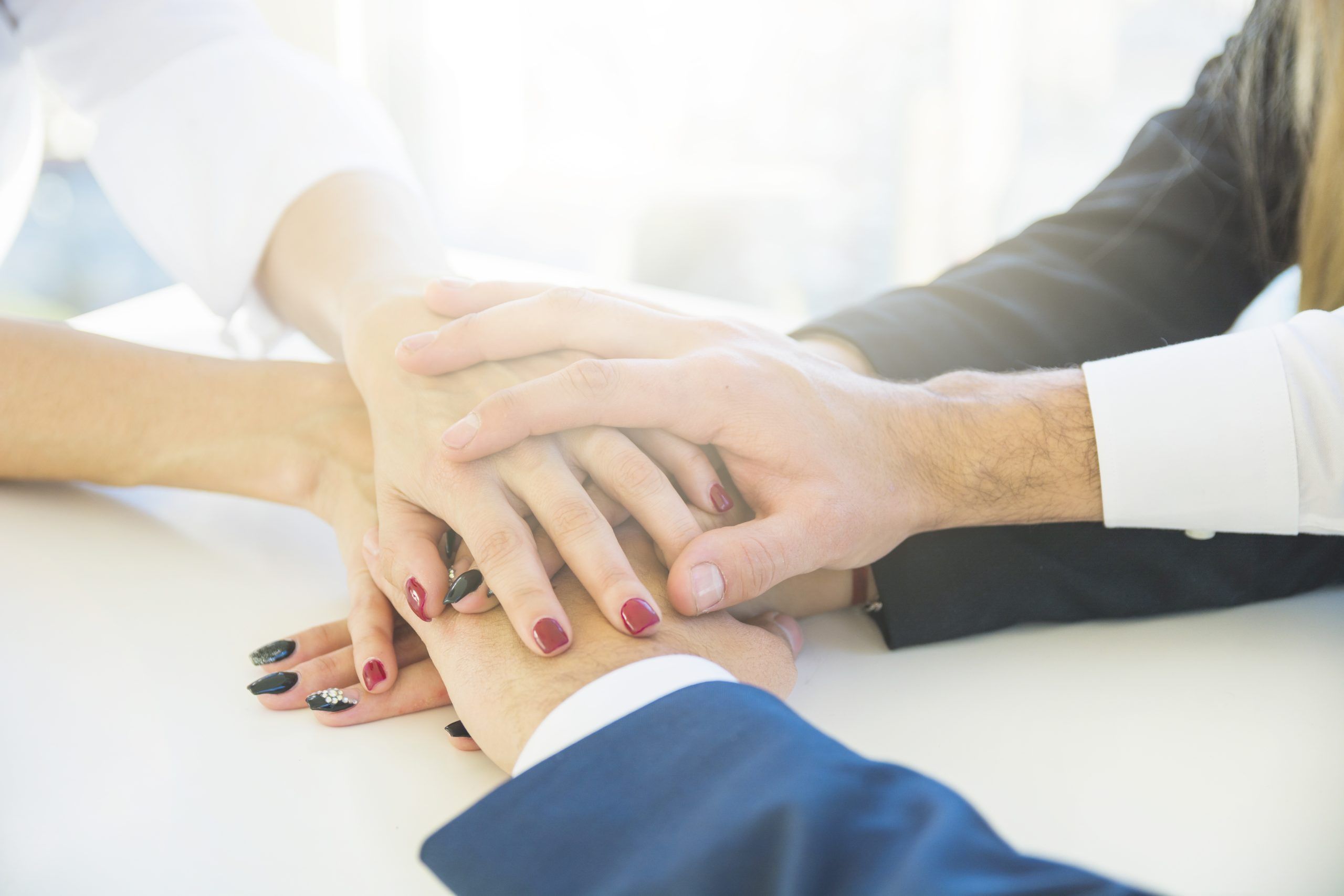 businesspeople-stacking-each-other-s-hand-white-desk