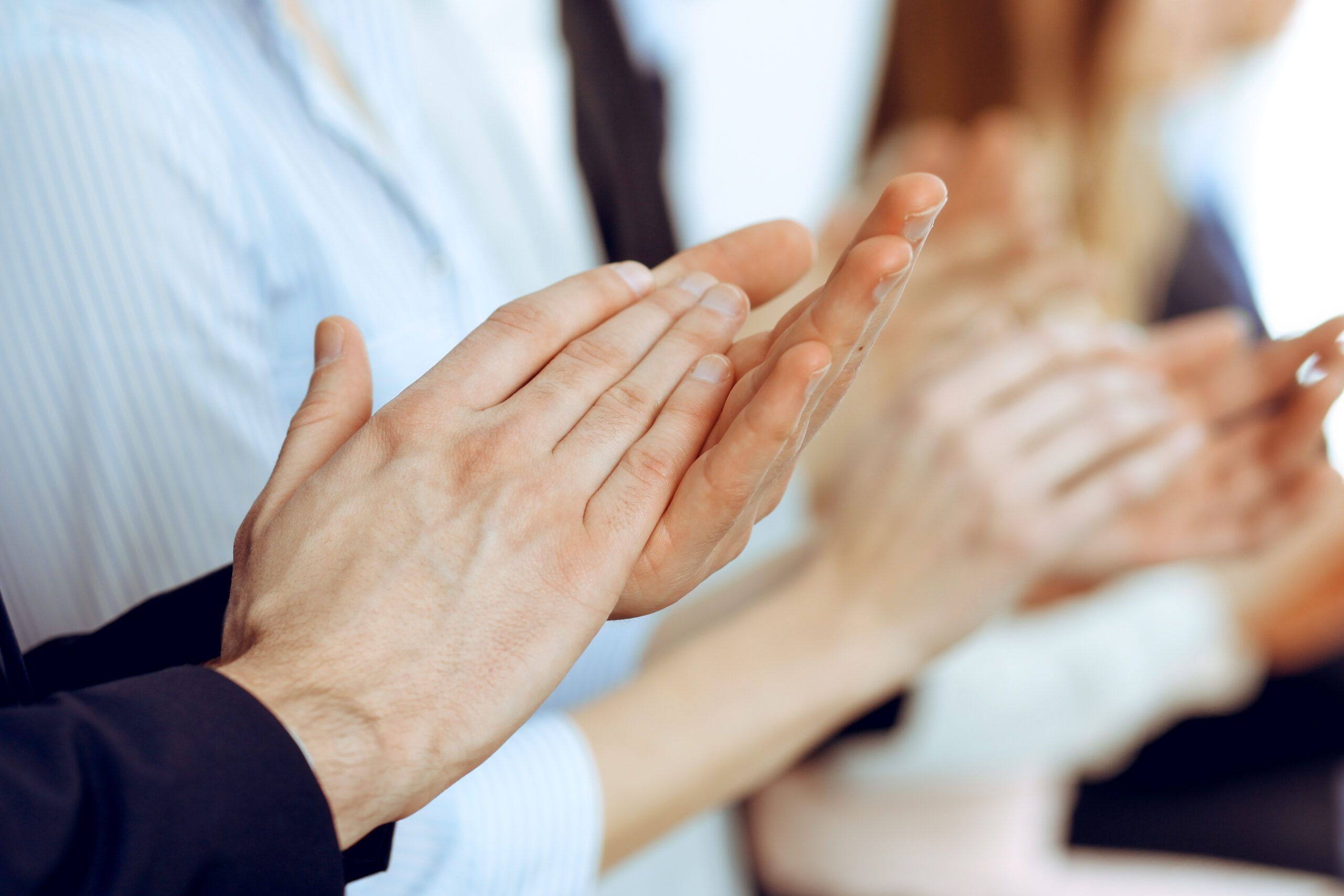 Business people clapping and applause at meeting or conference, close-up of hands. Group of unknown businessmen and women in modern white office. Success teamwork or corporate coaching concept